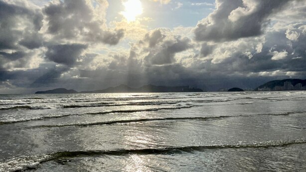 Een strand met golven en een bewolkte lucht.