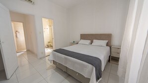 Een slaapkamer met een bed, nachtkastjes en een airconditioning.