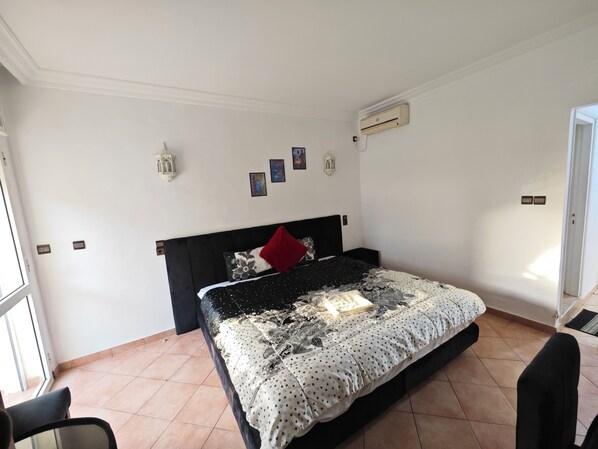 A bedroom with a bed, a chair, a window, and a door. - Hotel Merry (Agadir)