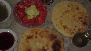 A table with various dishes including flatbreads, a salad, and a bowl of sauce.