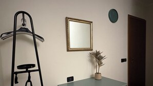 A room with a wardrobe, a coat rack, a mirror, and a potted plant. - Gardaland & Lake Apt with parking lot (Cavalcaselle)