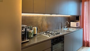 A modern kitchen with a built-in gas stove, a microwave, and a toaster. - Gardaland & Lake Apt with parking lot (Cavalcaselle)