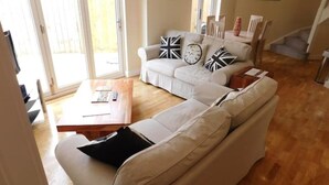 Olohuoneessa on beige sohva, sohvapöytä sekä ruokailutila, jossa on pöytä ja tuolit.