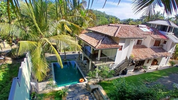 A two-story house with a swimming pool, surrounded by lush greenery and palm trees. - Unawatuna Heritage Villas (Unawatuna)
