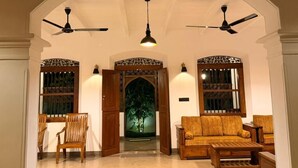A spacious living area with a high ceiling, two ceiling fans, a wooden sofa, a coffee table, and a dining area with chairs. - Unawatuna Heritage Villas (Unawatuna)