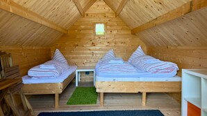 Een gezellig zolderkamer met twee houten stapelbedden, een klein tafeltje en een groene vloerkleed.
