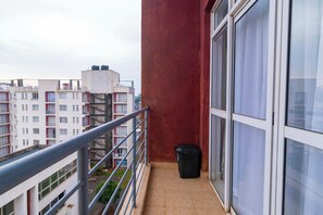 Ein Balkon mit Metallgeländer, einer Mülltonne und Blick auf die Nachbargebäude.