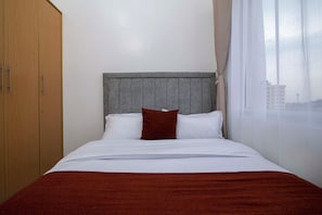 Ein Hotelzimmer mit einem Bett, einem Holzschrank und einem Fenster mit Blick auf Gebäude.