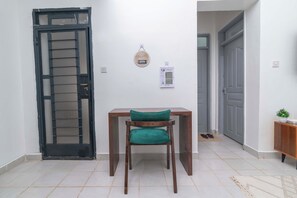 Ein Zimmer mit einem Holztisch, einem grünen Stuhl, einer Tür und einem an der Wand befestigten Schild.