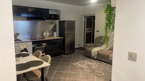 Un espacio habitable compacto con kitchenette, comedor y zona de estar.