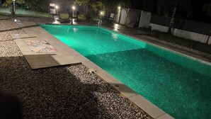 Una piscina rectangular con borde de azulejos, rodeada por un borde de guijarros y una zona de terraza también con azulejos.