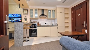 A modern kitchen with a built-in oven, a coffee machine, and a TV displaying a sports channel. - North Gate Avenue (Yerevan)