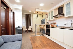 A modern kitchen with white cabinets, a wooden dining table, and a bar stool. - North Gate Avenue (Yerevan)
