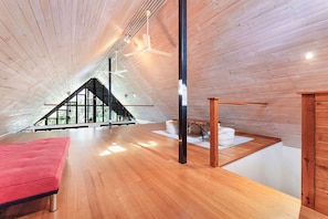A modern interior with a sloped ceiling, wooden flooring, and a red sofa.