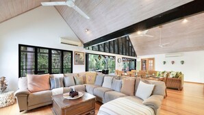A spacious living room with a high ceiling, large windows, and a cozy seating area. - Zenlux Tropical Retreat Pool BBQ Golf Course (Darwin)