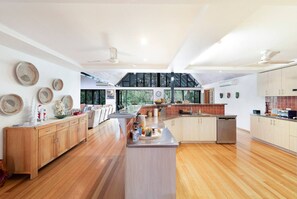 A spacious kitchen with wooden cabinets, a central island, and a large window providing a view of greenery outside.