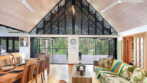 A spacious living area with a high ceiling, wooden flooring, a dining table with chairs, a sofa, and a coffee table. - Zenlux Tropical Retreat Pool BBQ Golf Course (Darwin)