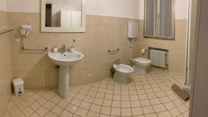 A bathroom with a sink, toilet, bidet, and mirror.