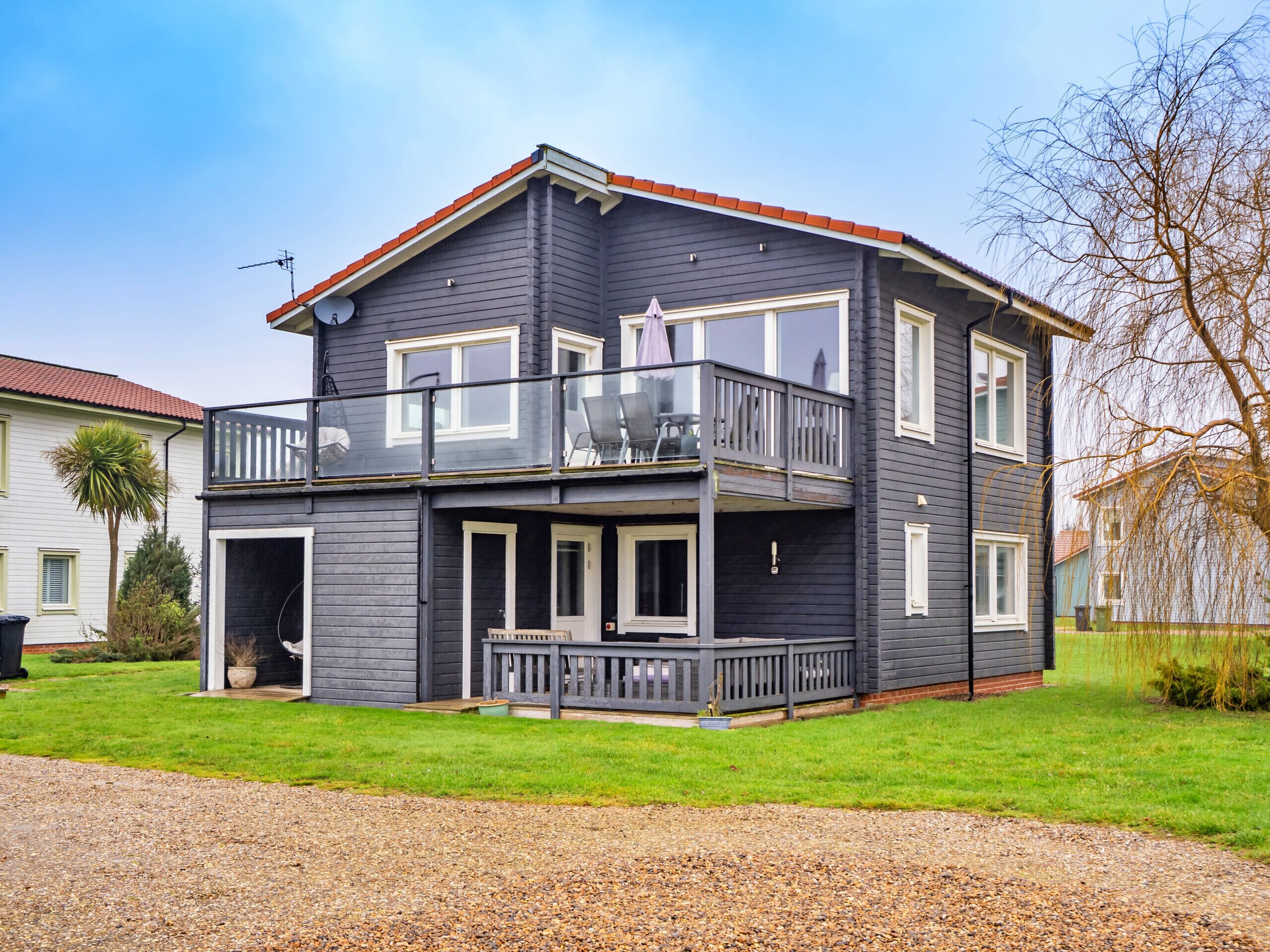 A two-story house with a balcony, a front porch, and a red roof.