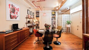 A modern dining area with a wooden table, red and black chairs, and a bookshelf filled with books and decorative items. - Bright Artist Loft in Williamsburg Brooklyn (Brooklyn)