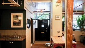 A narrow hallway with a wooden floor, a sink, and a stool. There is a door at the end of the hallway leading to a dark room. - Bright Artist Loft in Williamsburg Brooklyn (Brooklyn)