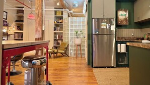A modern kitchen with a stainless steel refrigerator, wooden flooring, and a green accent wall. - Bright Artist Loft in Williamsburg Brooklyn (Brooklyn)