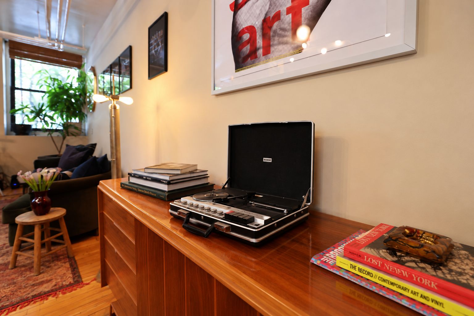 Una habitación con un escritorio de madera, un tocadiscos y un libro titulado 'The Lost New York'.