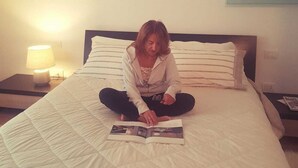 A person sitting on a bed with a magazine, in a room with a painting on the wall and a lamp on the nightstand. - At 900 mt. Spa, 1 km the sea, Oltremare/Aquafan, 10 min. walk, 5 min. by bike (Riccione)