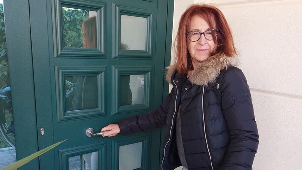 A person standing at a green door with a keyhole, wearing a black jacket with a fur collar, white pants, and patterned sneakers. - At 900 mt. Spa, 1 km the sea, Oltremare/Aquafan, 10 min. walk, 5 min. by bike (Riccione)
