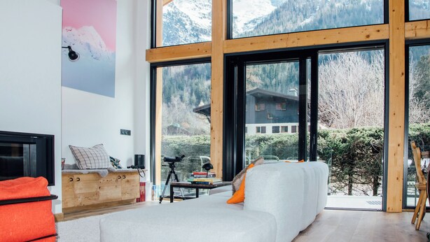 A modern living room with a large window, wooden beams, a sofa, a coffee table, and a bookshelf. - Chalet aux ours with Aiguille du Midi view, ideal for families (7mn from the center) (Les Houches)
