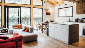 A modern kitchen with a central island, large windows, and a dining area with a wooden table and chairs. - Chalet aux ours with Aiguille du Midi view, ideal for families (7mn from the center) (Les Houches)