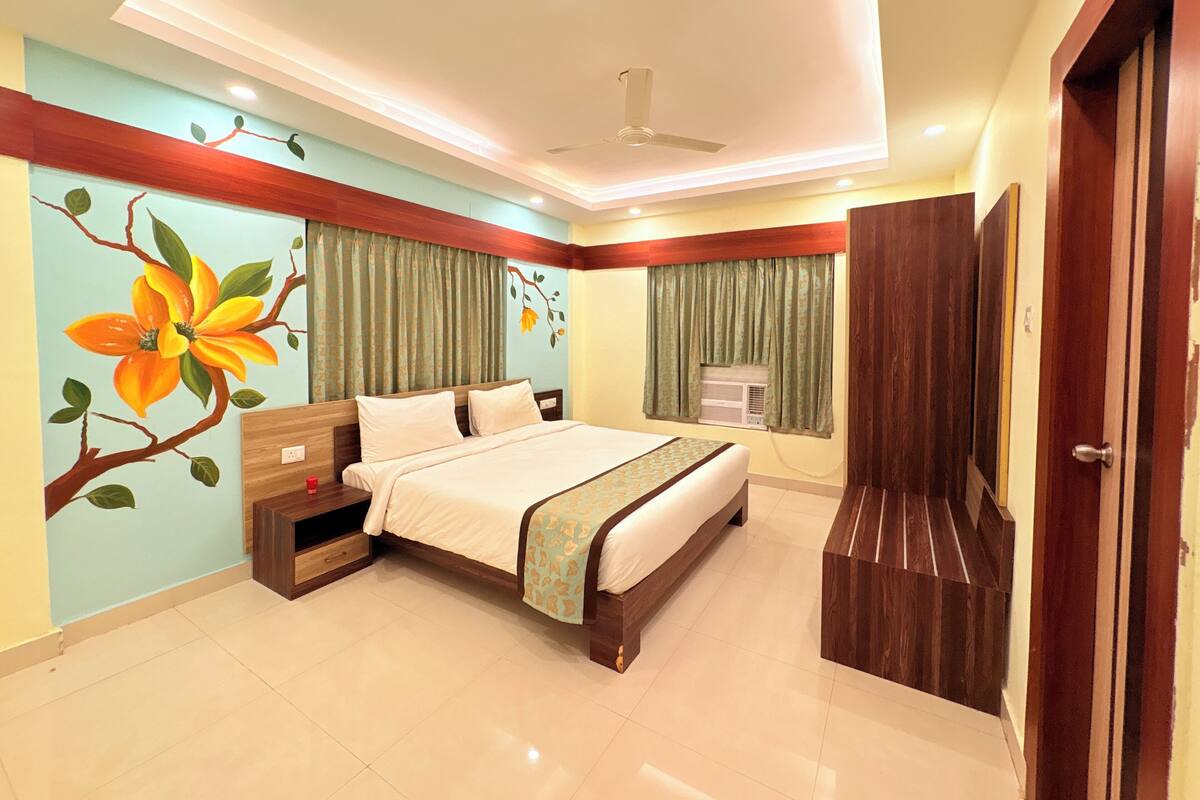 A bedroom with a bed, a nightstand, a dresser, a window with curtains, and a ceiling fan.
