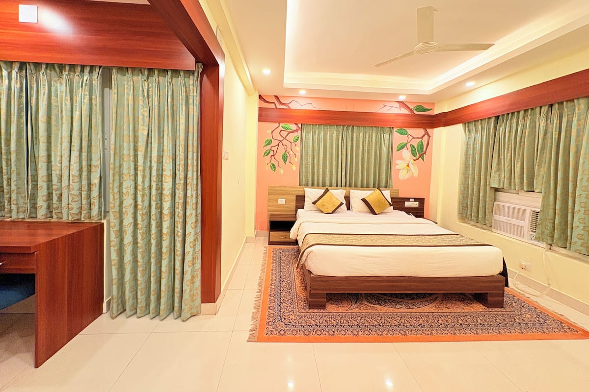 A bedroom with a bed, a desk, and a ceiling fan.