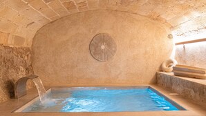 A stone-walled indoor pool with a clear water surface, a fan, and a stone bench. - Room '102 - Doble Deluxe Con Balcón' with Mountain View, Wi-Fi and Air Conditioning (Capdepera)