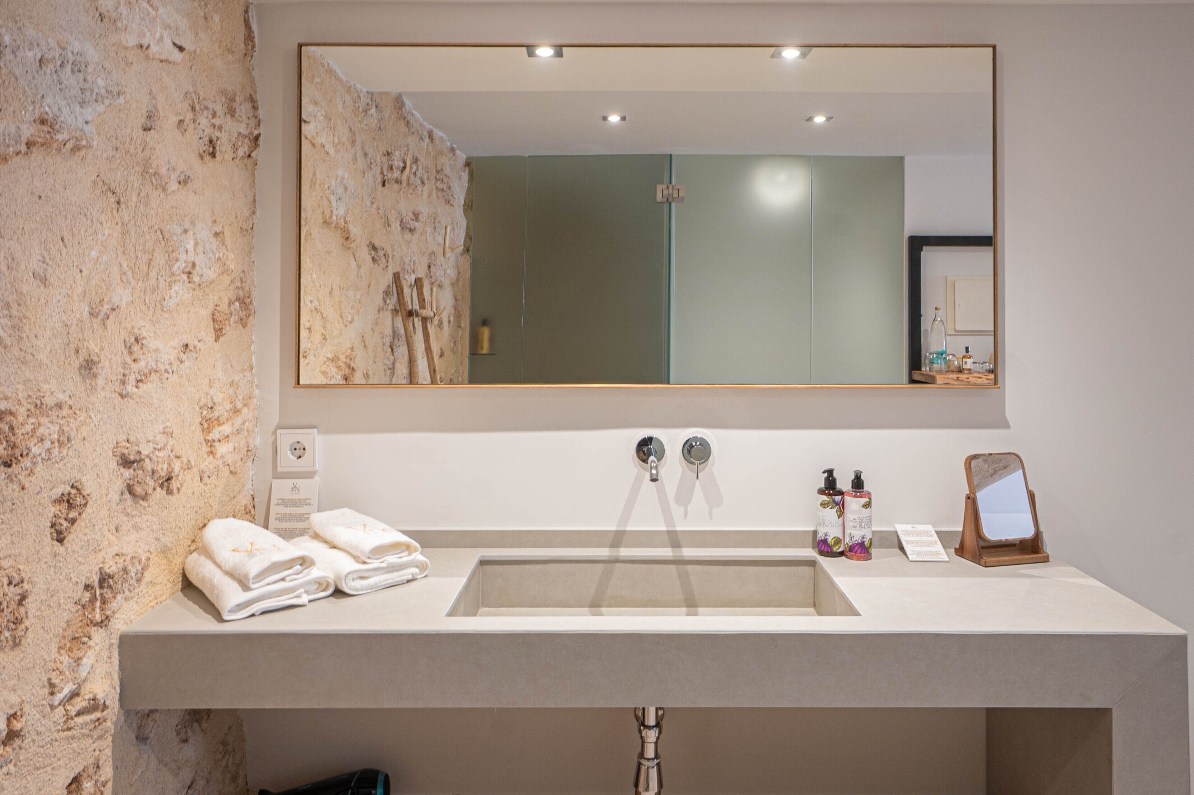 A bathroom with a large mirror, a sink, and towels on the counter.