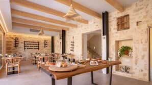 A rustic interior with exposed stone walls, wooden beams, and a long dining table with food and drinks. - Room '102 - Doble Deluxe Con Balcón' with Mountain View, Wi-Fi and Air Conditioning (Capdepera)