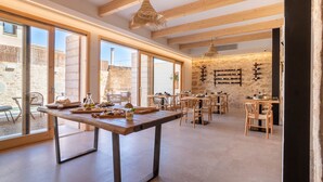 A spacious dining area with large windows, wooden beams, and a rustic stone wall. - Room '102 - Doble Deluxe Con Balcón' with Mountain View, Wi-Fi and Air Conditioning (Capdepera)