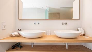 A bathroom with two white vessel sinks, a large mirror, and a wooden vanity.