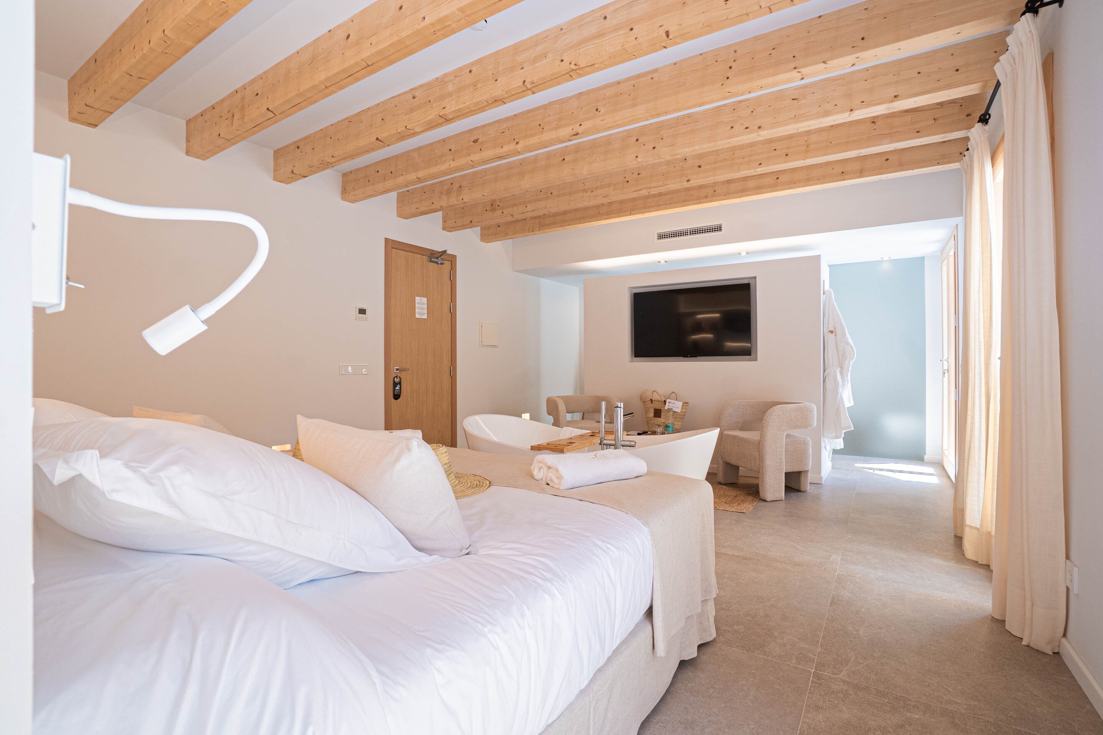 Ein Schlafzimmer mit Bett, Schreibtisch, Stuhl, Fernseher und einem Badezimmer mit Badewanne.