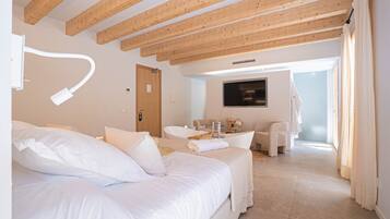 Ein Schlafzimmer mit Bett, Schreibtisch, Stuhl, Fernseher und einem Badezimmer mit Badewanne.