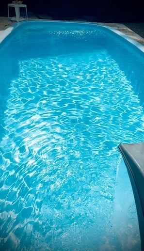 A swimming pool with clear blue water and a curved edge.