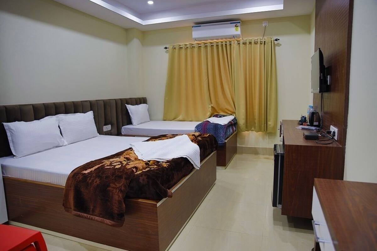 Een hotelkamer met twee bedden, een bureau, een televisie en een airconditioner.