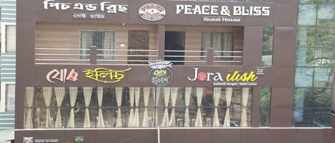 A building with multiple signs, including "Peace & Bliss Guest House" and "Jora Bliss Authentic Bengali Multi Cuisine."