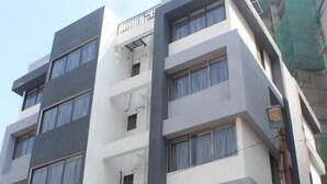 A multi-story building with a modern architectural design, featuring a combination of white and dark grey facades, multiple balconies, and air conditioning units on the exterior. - Zenora Stays (Pune)
