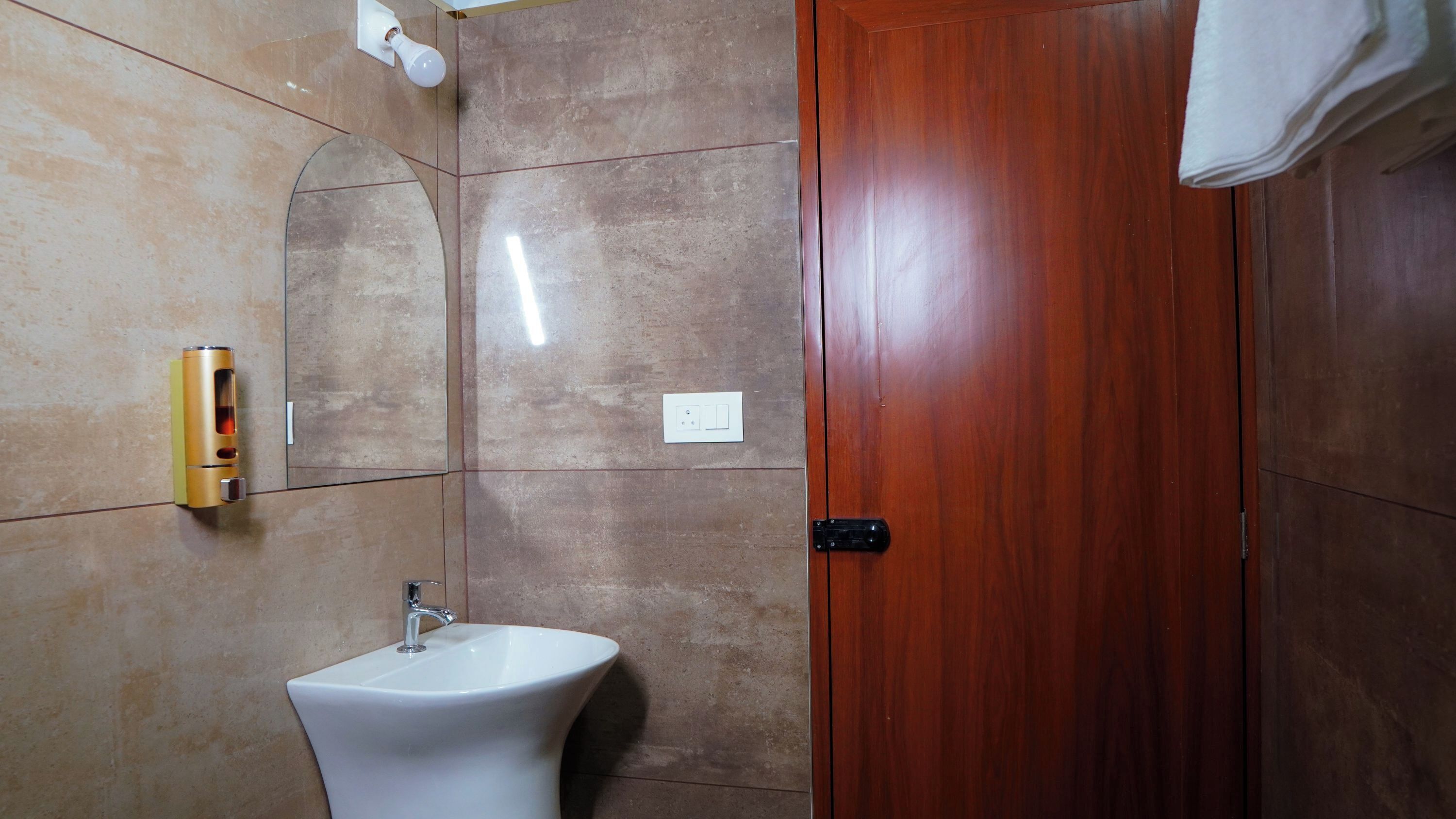 Un bagno con un lavandino, un dispenser per asciugamani e una porta in legno.