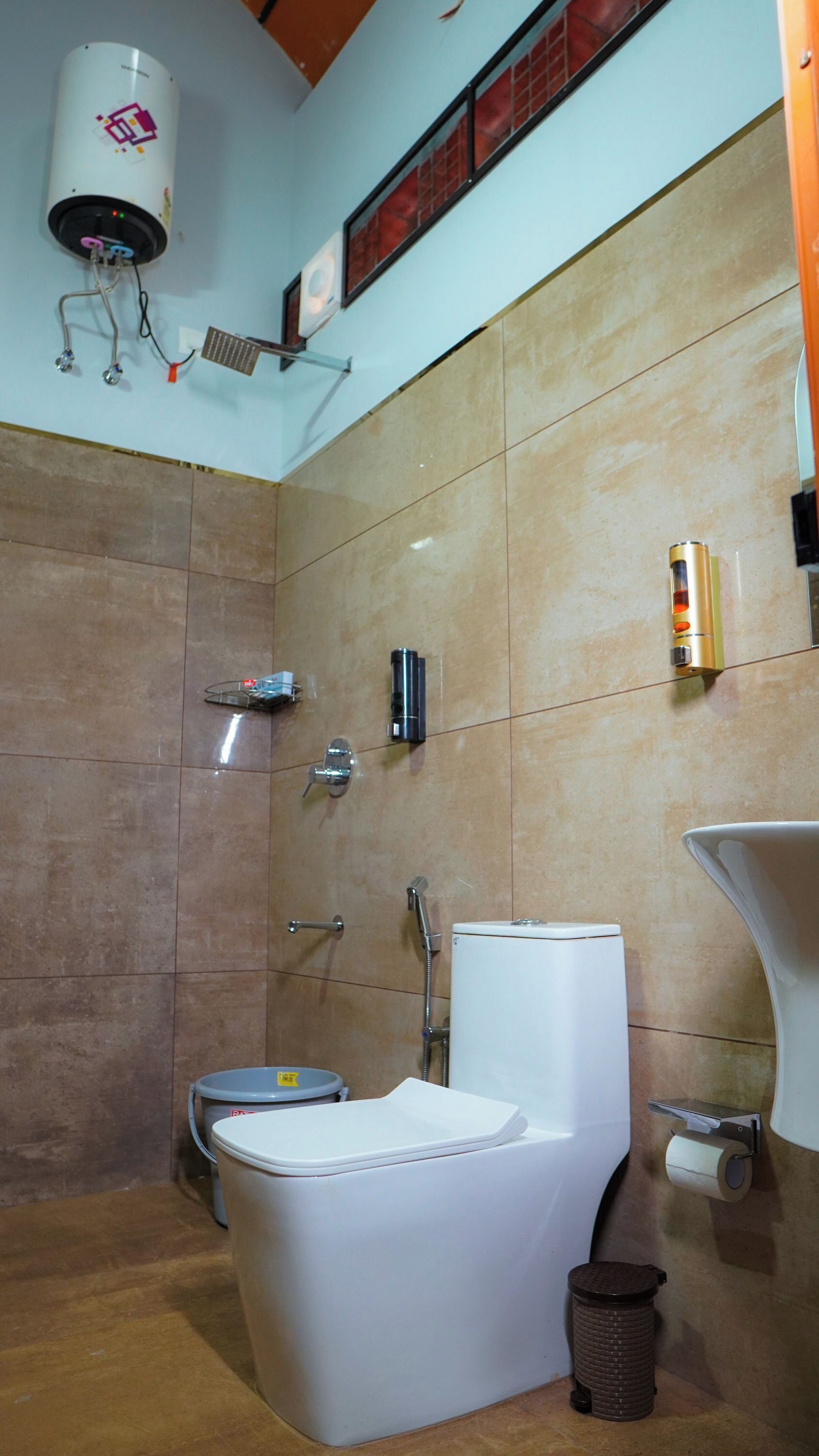 Un baño con inodoro, bidé y un secamanos fijado a la pared.