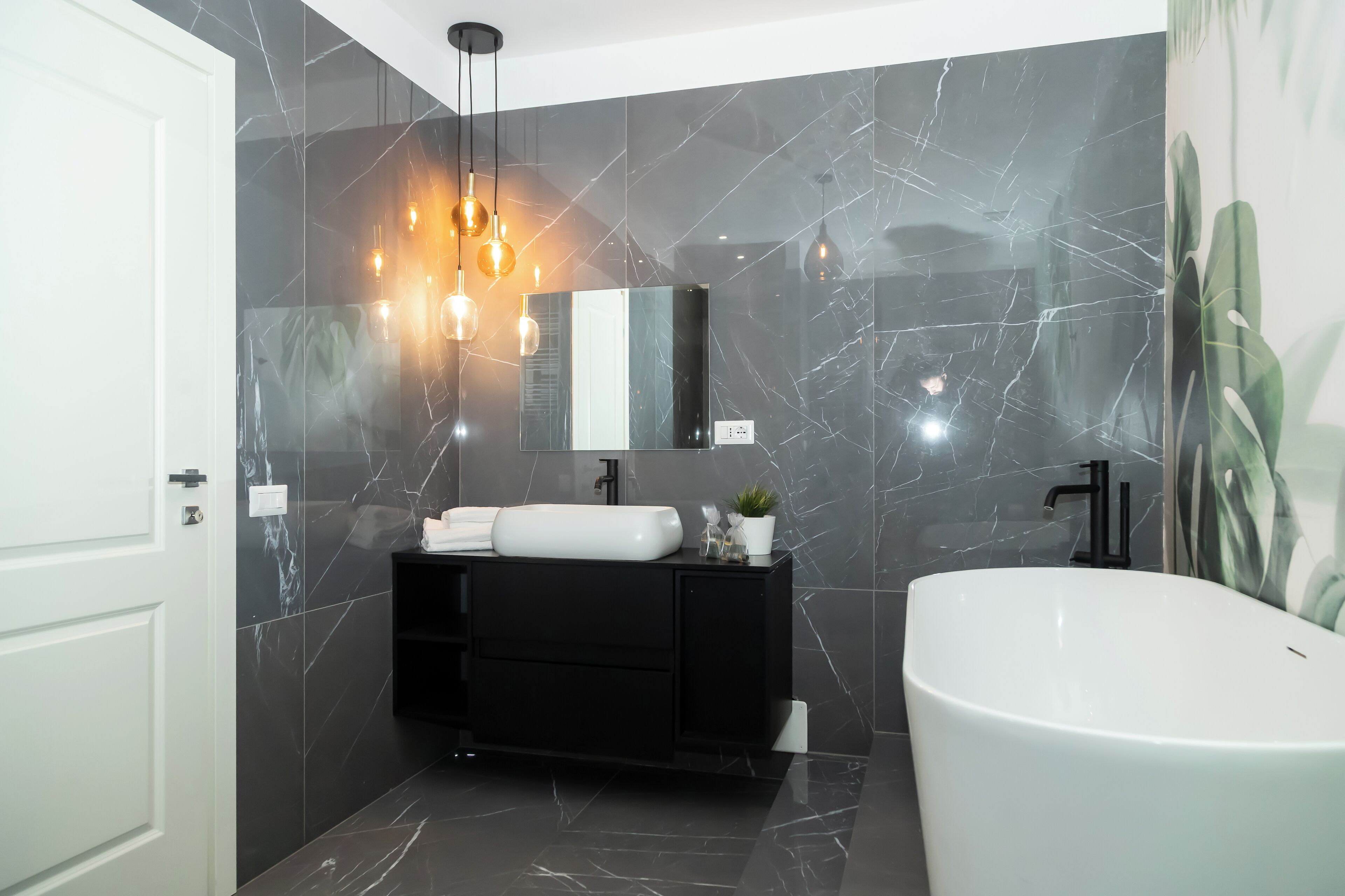 A modern bathroom with a black vanity, white sink, and a freestanding bathtub.