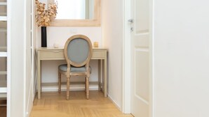 A narrow hallway with a wooden desk, a chair, and a mirror.