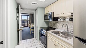 A compact kitchen with a stove, microwave, sink, and cabinets. - Salt life made Simple at Grande Shores (Myrtle Beach)