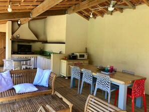 A rustic kitchen with wooden beams, a dining area with a wooden table and chairs, and a cozy seating area with cushions.